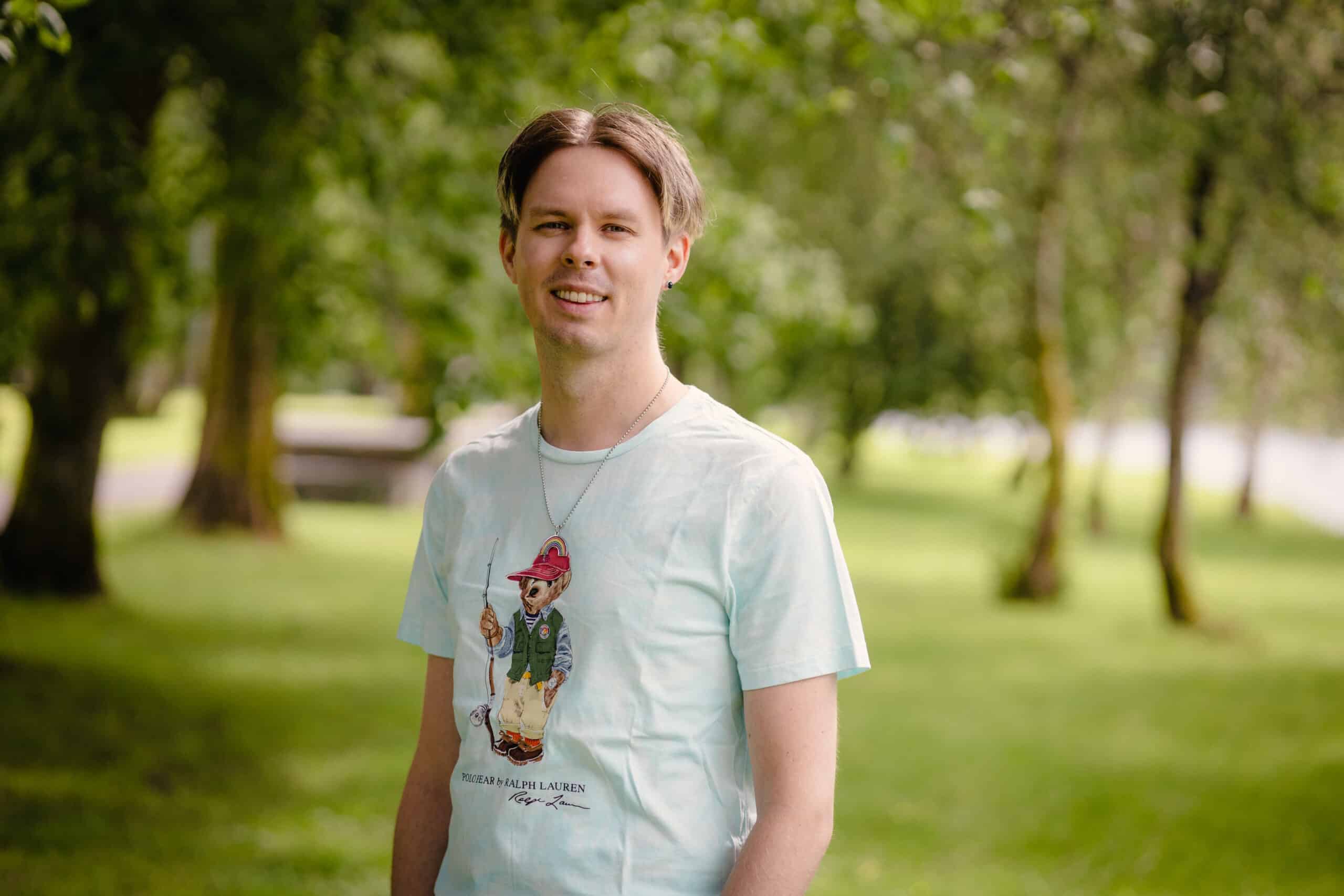 Portrettbilde av Håvard Solbakken, ung mann, ute i en grønn park.